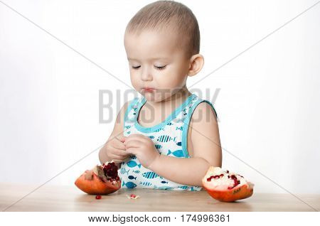 Baby eats a pomegranate ripe and juicy very tasty and joyfully