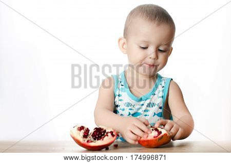 Baby eats a pomegranate ripe and juicy very tasty and joyfully