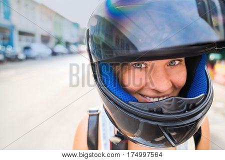 Portrait of a girl close-up of a head in a helmet with an open glass. Happy girl in helmet with good mood on a street background in the afternoon.