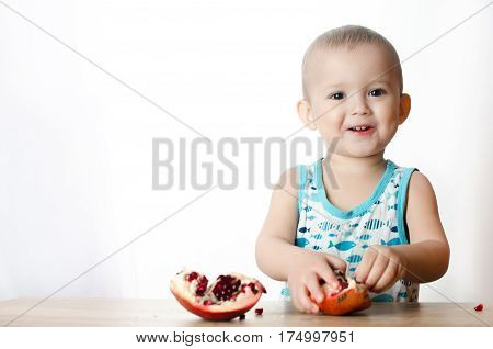 Baby eats a pomegranate ripe and juicy very tasty and joyfully