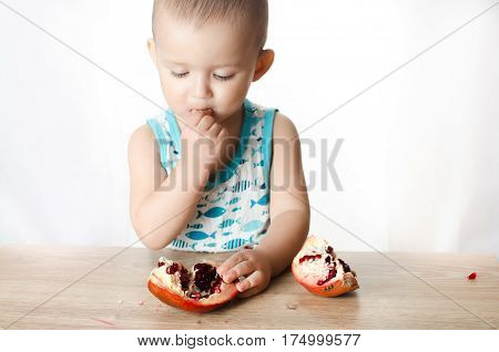 Baby eats a pomegranate ripe and juicy very tasty and joyfully