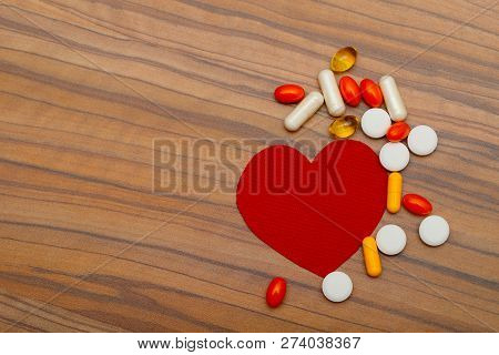 Red Heart And Many Bright Pills Drugs On Wooden Background. Cropped Shot, Horizontal, Side View. Con