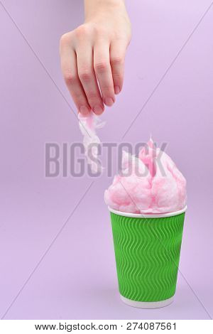 Bright Pink Candy Cotton In Plastick Cup In Woman Hand On Lilac Background.