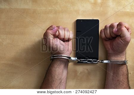 Crime Concept In The Network. Shaking Hands Holding A Mobile Phone.