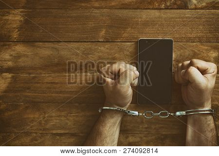 Crime Concept In The Network. Shaking Hands Holding A Mobile Phone.