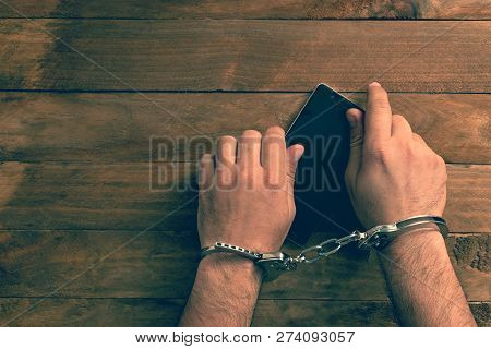 Crime Concept In The Network. Shaking Hands Holding A Mobile Phone.