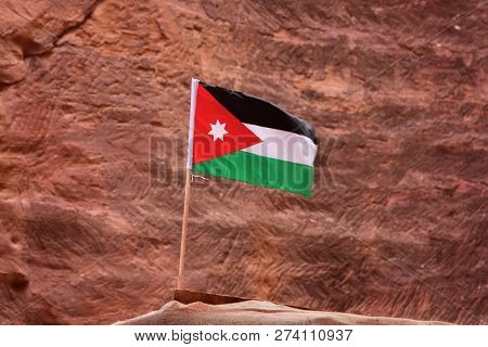 The Flag Of Jordan, Shooting In The Ancient Stone City Petra, On The Red Rock Background, Close-up, 