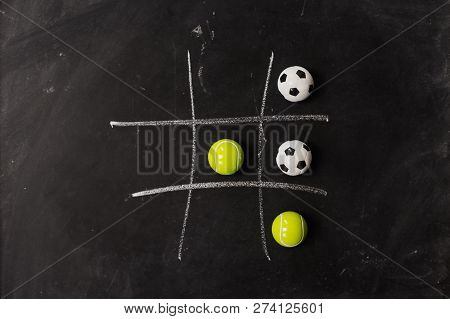 Tennis Vs Football Tic Tac Toe Game Competition. Challenge Concept On Black Chalk Board