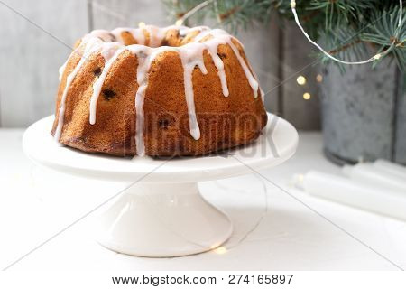 Pie With Raisins And Icing From Powdered Sugar On The Background Of Fir Branches And Garlands. Rusti