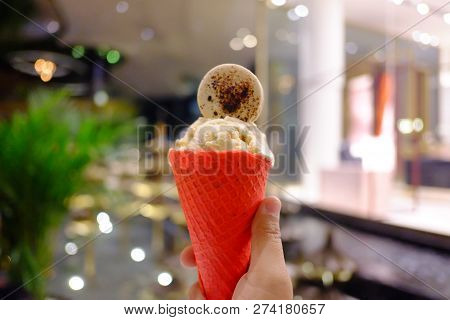 Close Up A Red Crispy Cone Of A Miky Ice Cream With Blue Macaroon On Top And Bokeh Light,blurred A D