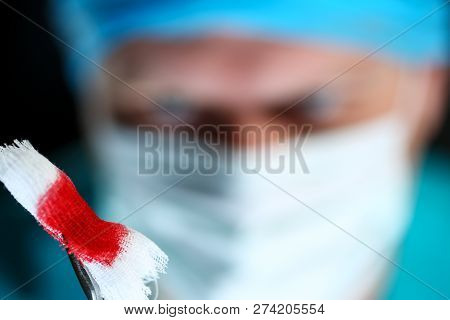 Surgeon In Sterile Uniform Arms Holding And Passing To Colleague Tools With Bio Material Wad Closeup