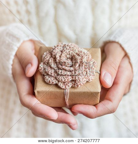 Woman In White Knitted Sweater Holding A Present Wrapped In Craf