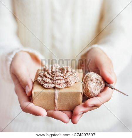 Woman In White Knitted Sweater Holding A Present Wrapped In Craf