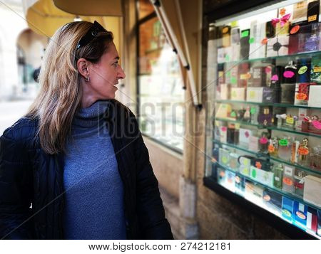 Woman Attracted By Shop Window Of A Perfumery Display Showcase .
