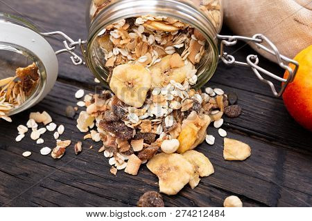 Homemade Granola In Glass Jar And Apples In Reusable Fabric Bag On Dark Wooden Table With Texture. H