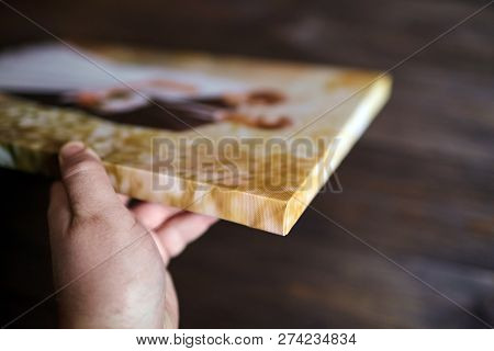 Male Hand Holding A Photography With Gallery Stretch On A Wooden Frame. Printed Wedding Photo On Can