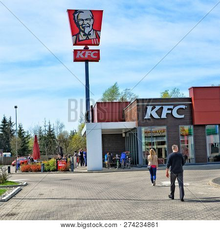 People Going To Kfc Restaurant. Fast Food Restaurant Chain On European Roads. Red Sign And Logo Of K
