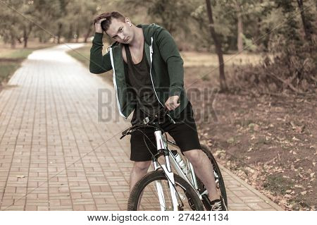 Portrait Of Romantic Young Caucasian Handsome Male With Dark Curly Hair Sitting On Bicycle Alone On 