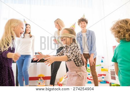 Positive Excited Blindfolded Girl In Party Hat Gesturing Hands While Catching Friends During Game, C