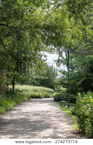 Lasalle, Quebec - August 15, 2018 -vertical Landscape A Woman Walking On A Path Surrounded By Trees 