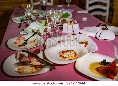 Messy Table With Dirty Dishes After Party On Food Table. Leftover Food, Empty Glasses, Dirty Dishes 