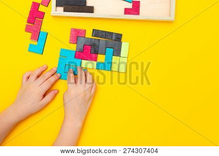 Wooden Puzzle And Kids Hands On Yellow Background. Copy Space