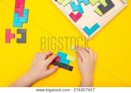 Wooden Puzzle And Kids Hands On Yellow Background. Flat Lay
