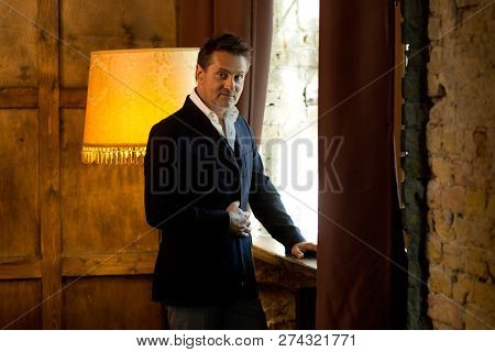 Calm Attractive Elegant Man Touching The Jacket On Him And Thoughtfully Looking At You While Standin
