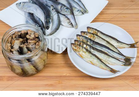 Smoked Baltic Herring On Saucer And Headless Baltic Herring Preserved In Vegetable Oil In Glass Jar 