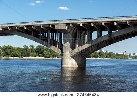 Concrete Bridge Pillar Arch Structure In River Water, Close-up Of The Support Structure And Columns.