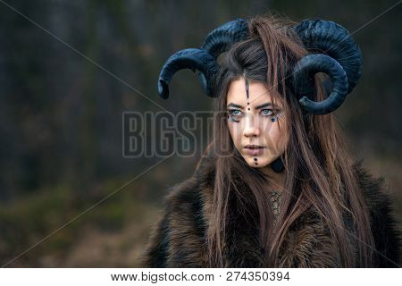 Outdoor Portrait Of Beautiful Young Woman Warrior With Blue Eyes And Specific Makeup Wearing Ram Hor