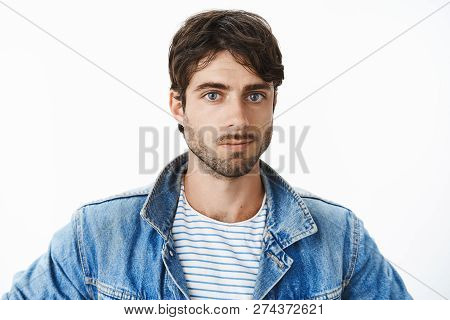 Headshot Of Attractive Young Hispanic Man With Blue Eyes And Beard In Denim Jacket Over Striped T-sh