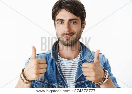Close-up Shot Of Satisfied And Happy Young Attractive Male With Blue Eyes And Bristle In Denim Jacke