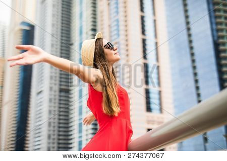 Portrait Of Young Woman In Red Dress, Sunglasses And Straw Hat With Raised Hands Enjoy The View On D
