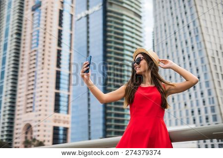 Portrait Of Young Smile Woman In Red Dress, Sunglasses And Summer Hat Take Selfie On The Phone On Do