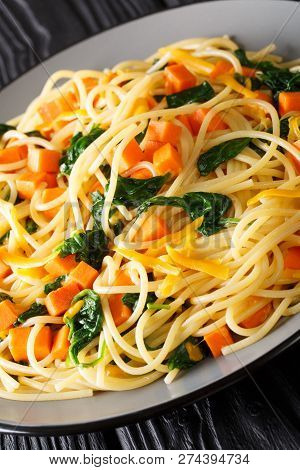 Spaghetti Pasta With Pumpkin, Spinach And Cheddar Cheese Close-up On A Plate. Vertical