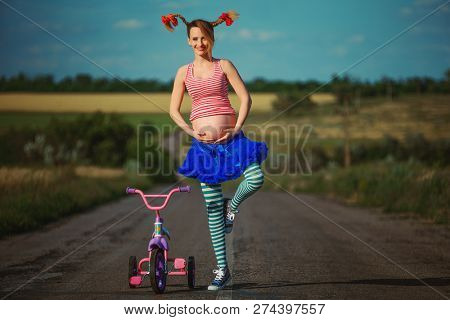 Happy pregnant Pippi Longstocking having fun during the walk in summer nature