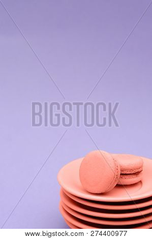 A Stack Of Saucers With Two Macaroons Of Coral Color On A Purple Background. Coral Color Is The Colo