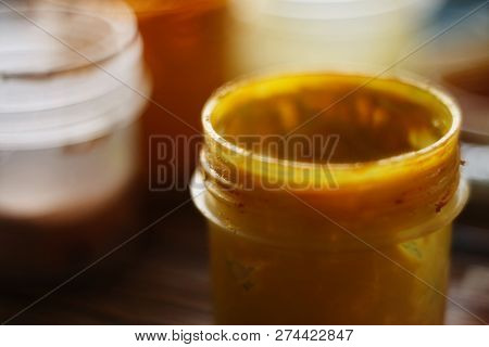 Open Jar With Yellow Gouache Stands Against The Background Of Other Jars