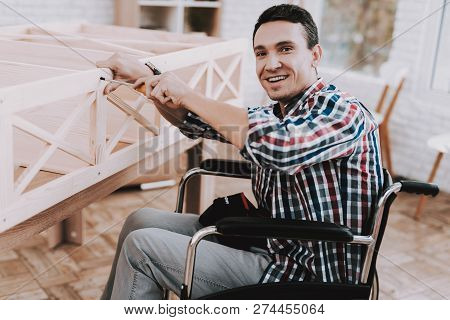 Young Man On Wheelchair Assembling Wooden Bookshelf At Home. Wooden Bookcase. Selfmade Furniture. Wh