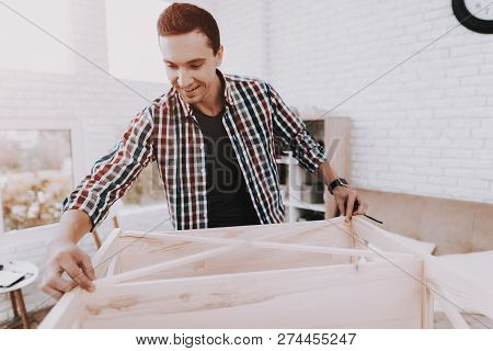 Young Man Assembling Wooden Bookshelf At Home. Wooden Bookcase. Selfmade Furniture. Man And Hobby. W