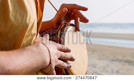 Man Playing On A Drum With His Hands, Close Up. Hands Tapping A Small Drum