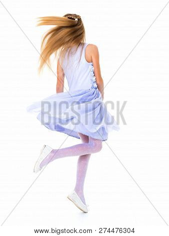 Happy Little Girl In A Lush Flowing Dress, Spinning. Her Hair Is Flying In The Wind. The Concept Of 