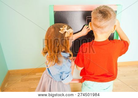 Little Preschoolers Writing On Black Board Indoors