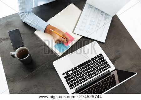 Top view of a woman working with laptop and documets at the table at home