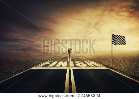 Competitive Young Woman On The Road Celebrate Waving Hand Raised Up Before Crossing The Finish Line.