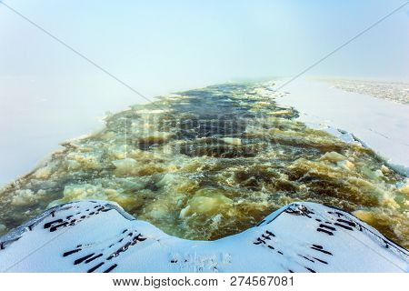 Wide strip of ice crumb spreads behind the icebreaker. Lapland. Unforgettable excursion to the arctic tourist cruise on the sea icebound. The concept of active and extreme tourism