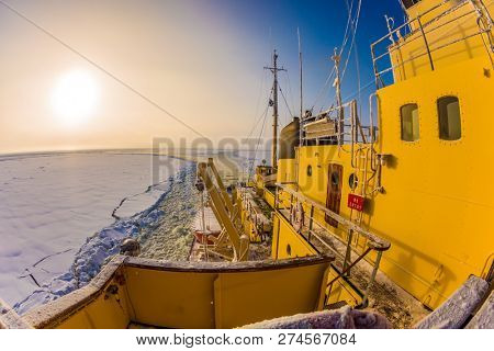 Winter morning in Lapland. The strip of ice crumb spreads behind the icebreaker. The excursion to the arctic tourist cruise on the sea icebound. The concept of active and extreme tourism