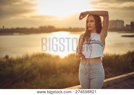 Young Beautiful Caucasian Girl Listening To Music With Smartphone Walking In The City With Headphone