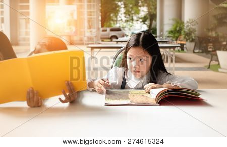 In Selectie Focus Of The Little Girl Is Reading Book,warm Light Tone,blurry Light Around